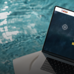 A laptop resting on a lounger next to water. The screen displays Aubrey's website